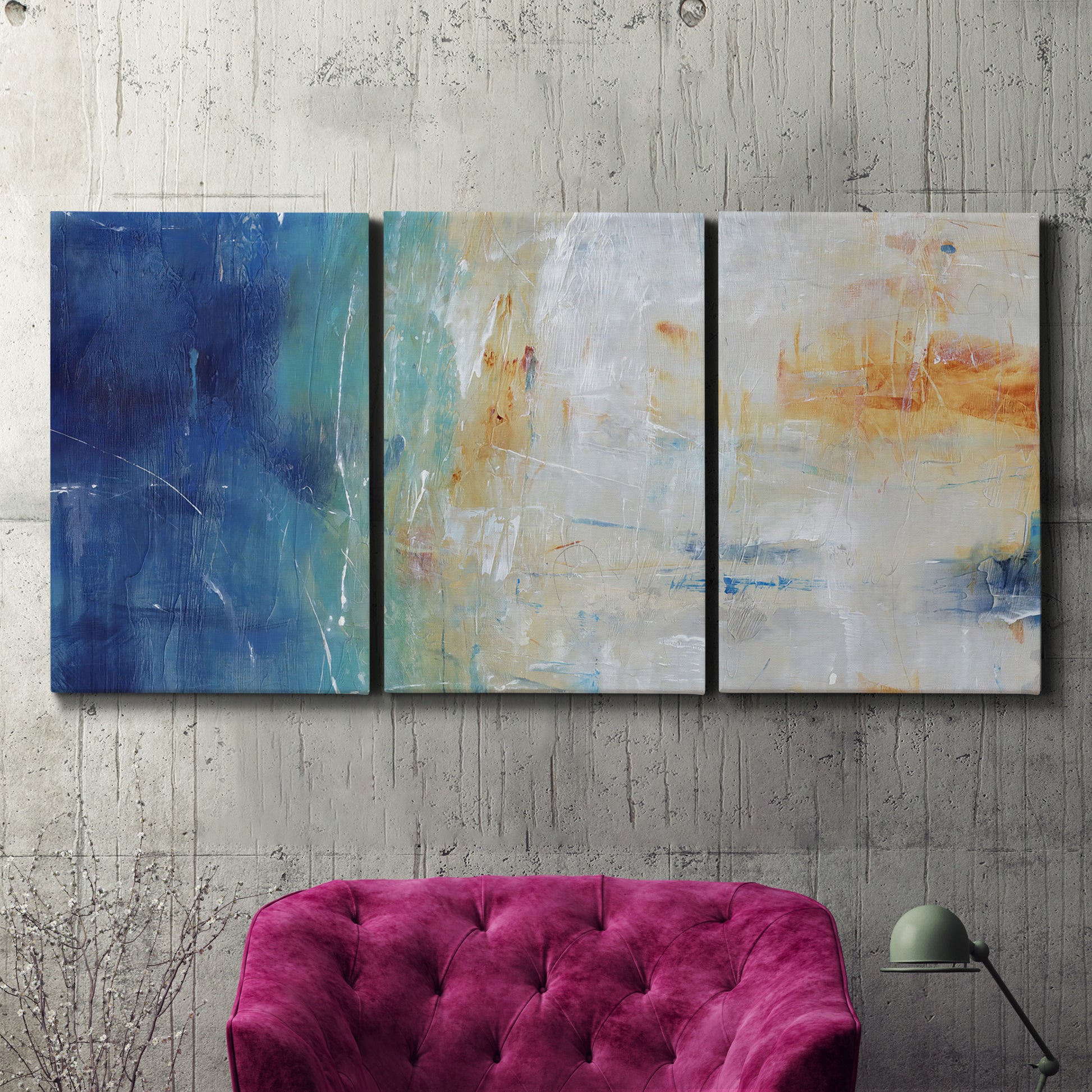 Three-panel canvas wall art featuring deep blue abstract grotto tones, displayed in a living room above a suede accent chair.