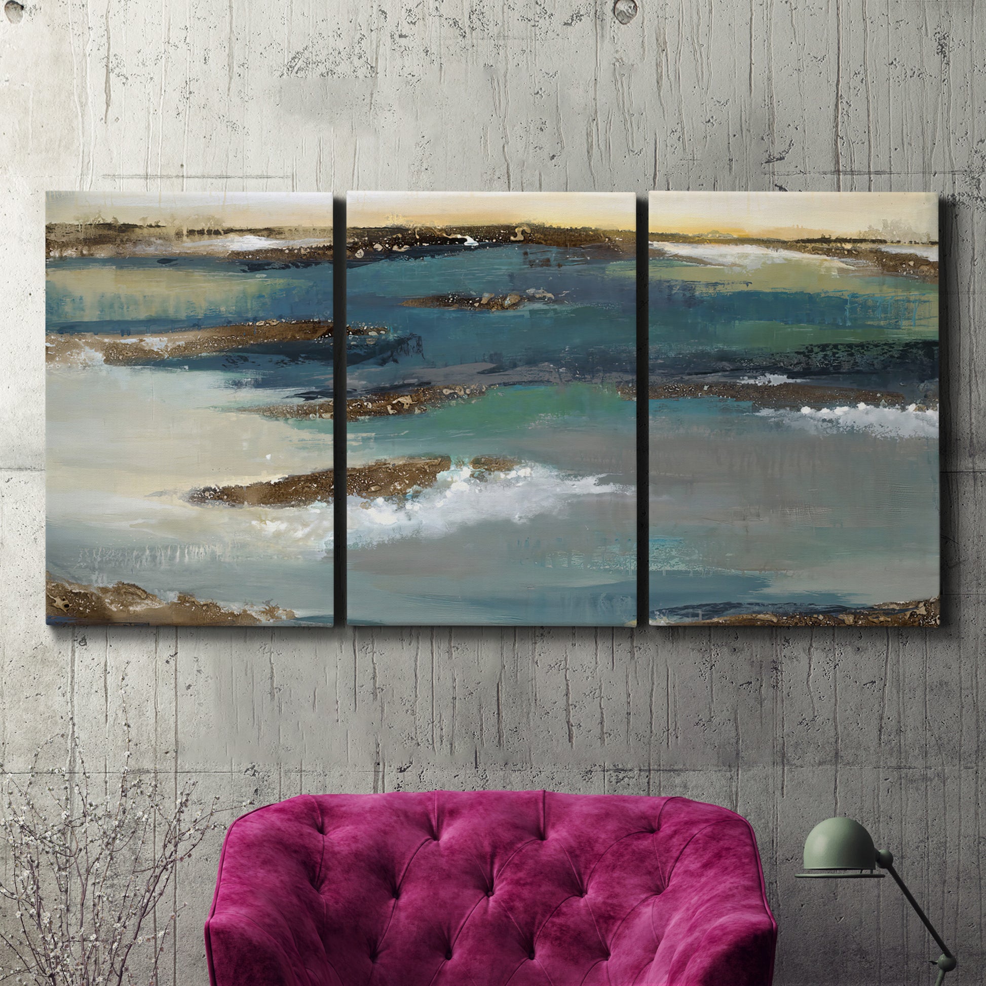 Three-panel canvas wall art featuring rocky coastal bluff above sea, displayed in a living room above a suede accent chair.