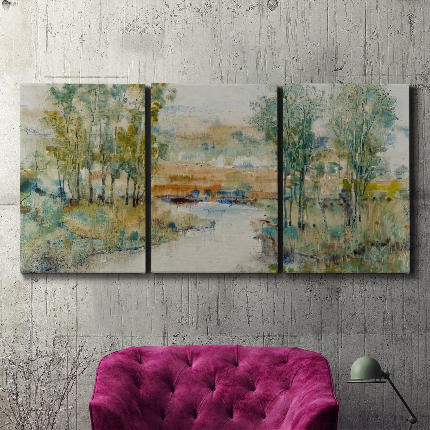 Three-panel canvas wall art featuring trees lining quiet creek, displayed in a living room above a suede accent chair.