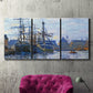 Three-panel canvas wall art featuring industrial dock along harbor, displayed in a living room above a suede accent chair.