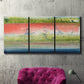 Three-panel canvas wall art featuring layered abstract color banding, displayed in a living room above a suede accent chair.