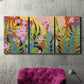 Three-panel canvas wall art featuring bold colorful floral abstraction, displayed in a living room above a suede accent chair.