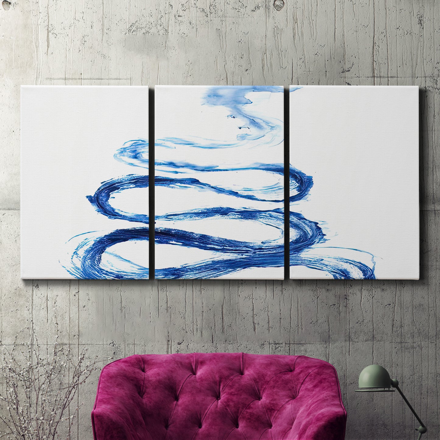 Three-panel canvas wall art featuring indigo abstract vapor watercolor, displayed in a living room above a suede accent chair.