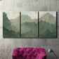 Three-panel canvas wall art featuring autumn storm over rolling landscape, displayed in a living room above a suede accent chair.