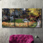 Three-panel canvas wall art featuring garden in full bloom by coast, displayed in a living room above a suede accent chair.