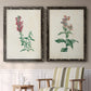 Set of two black barnwood framed canvas prints depicting two vintage botanical studies of flowering stems with detailed green leaves on aged cream paper above a sideboard in a cozy sitting room.
