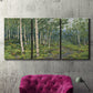 Three-panel canvas wall art featuring woodland forest scene with tall trees, displayed in a living room above a suede accent chair.