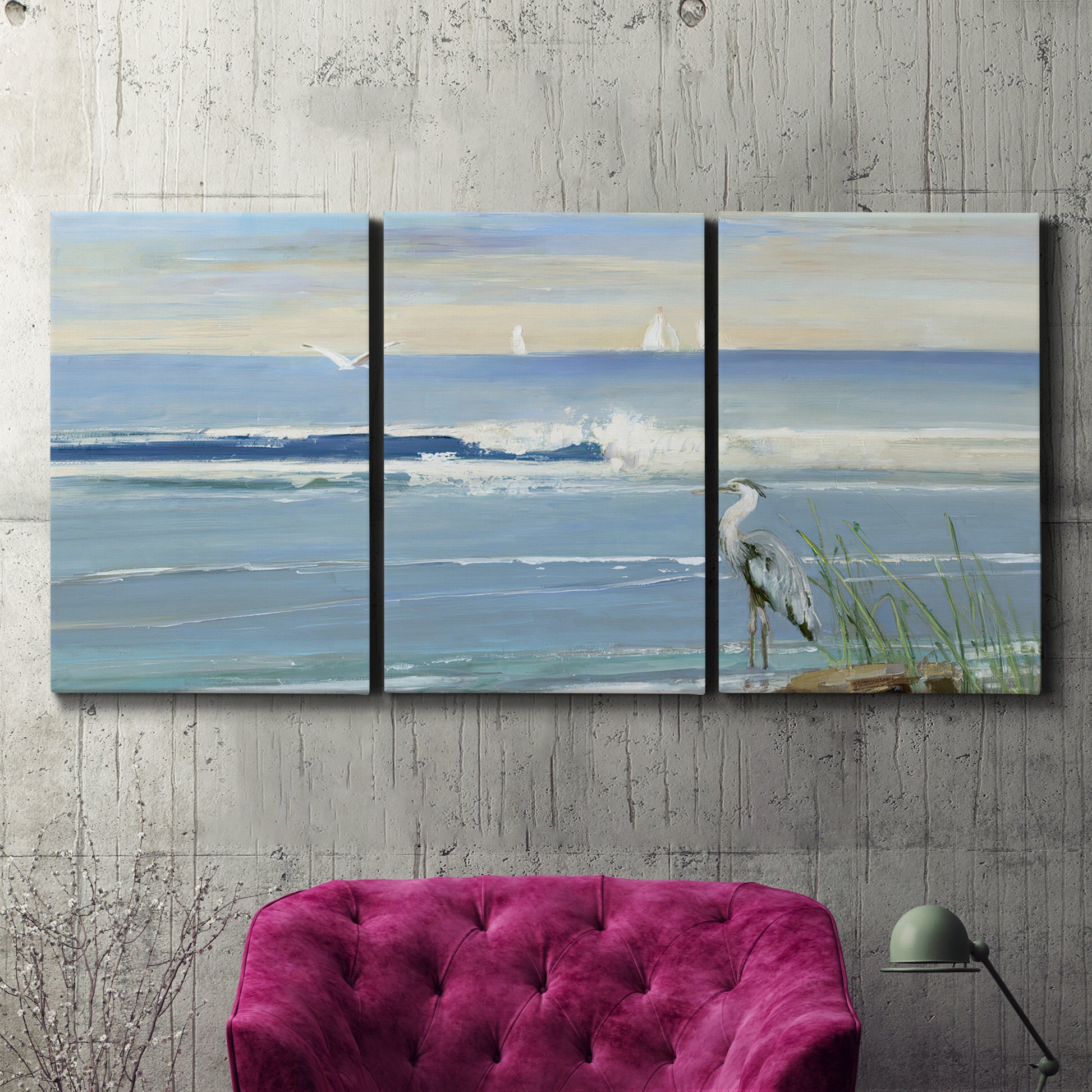 Three-panel canvas wall art featuring sunrise reflecting across bay waters, displayed in a living room above a suede accent chair.