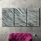 Three-panel canvas wall art featuring coastal shoreline with gentle surf, displayed in a living room above a suede accent chair.