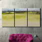 Three-panel canvas wall art featuring abstract terrace landscape view, displayed in a living room above a suede accent chair.