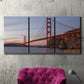 Three-panel canvas wall art featuring golden gate bridge spanning bay, displayed in a living room above a suede accent chair.