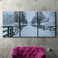 Three-panel canvas wall art featuring snow covered rural road photograph, displayed in a living room above a suede accent chair.