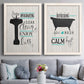 Set of two white barnwood framed canvas prints depicting paired graphic bathroom word art with black tubs, hand-lettered phrases, and small teal accents above a sofa in a contemporary living room.