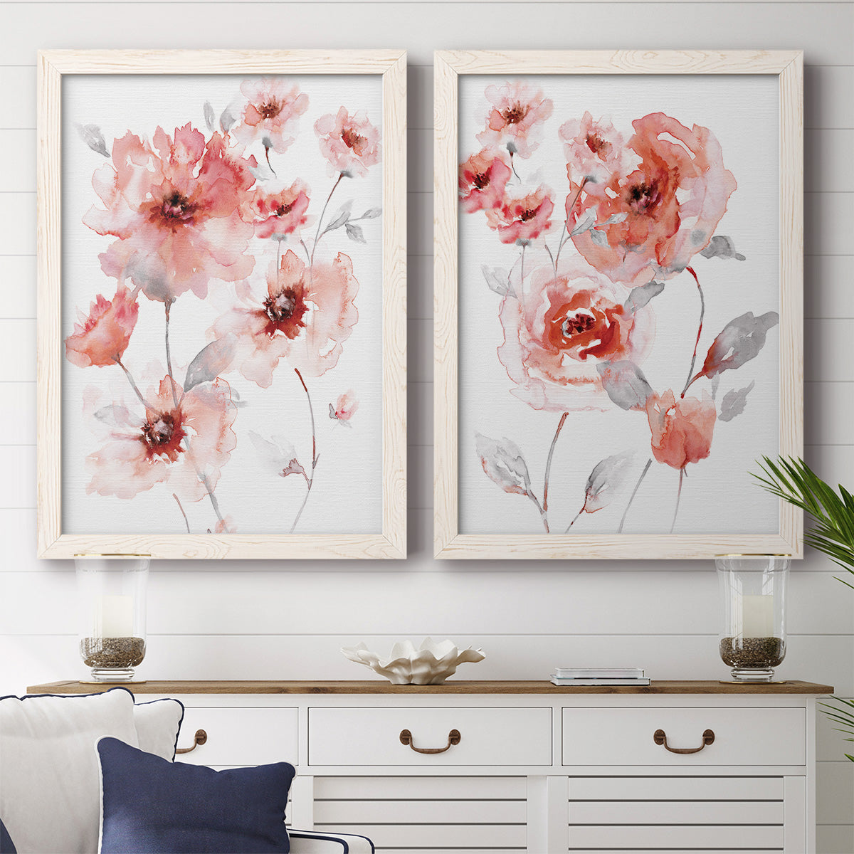 Set of two white barnwood framed canvas prints depicting a coordinated art pair of loose coral pink blossoms on slender gray stems rendered as airy contemporary watercolor florals above a dining room sideboard.