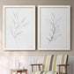Set of two white barnwood framed canvas prints depicting two minimalist botanical line drawings featuring single continuous-line leafy branches above a sideboard in a cozy sitting room.