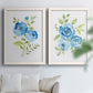 Set of two white barnwood framed canvas prints depicting open blossoms, delicate stems, and crisp white backgrounds arranged across two complementary compositions above a sofa in a bright living space.