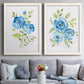 Set of two white barnwood framed canvas prints depicting paired contemporary botanical paintings with open blossoms, delicate stems, and crisp white backgrounds above a sofa in a contemporary living room.