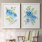 Set of two white barnwood framed canvas prints depicting two contemporary botanical paintings featuring blue watercolor flowers with fresh green leaves above a sideboard in a cozy sitting room.