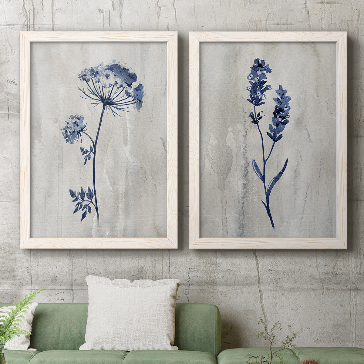 Set of two white barnwood framed canvas prints depicting a coordinated art pair of blue wildflower stems on weathered neutral paper rendered as rustic monochrome botanical paintings above a sofa in a modern living room.