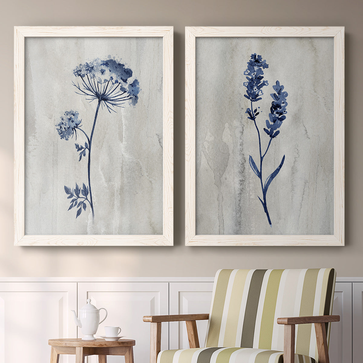 Set of two white barnwood framed canvas prints depicting two rustic monochrome botanical paintings featuring blue wildflower stems on weathered neutral paper above a sideboard in a cozy sitting room.