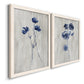 Angled view of a set of two white barnwood framed canvas prints featuring two rustic monochrome botanical paintings featuring blue wildflower stems on weathered neutral paper.