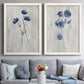 Set of two white barnwood framed canvas prints depicting paired rustic monochrome botanical paintings with indigo blossoms, thin stems, and softly distressed gray backgrounds above a sofa in a contemporary living room.