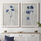Set of two white barnwood framed canvas prints depicting a coordinated art pair of blue wildflower stems on weathered neutral paper rendered as rustic monochrome botanical paintings above a dining room sideboard.