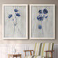 Set of two white barnwood framed canvas prints depicting two rustic monochrome botanical paintings featuring blue wildflower stems on weathered neutral paper above a sideboard in a cozy sitting room.