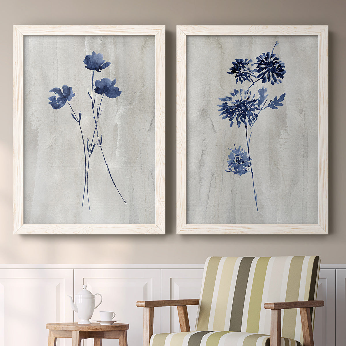 Set of two white barnwood framed canvas prints depicting two rustic monochrome botanical paintings featuring blue wildflower stems on weathered neutral paper above a sideboard in a cozy sitting room.