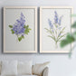 Set of two white barnwood framed canvas prints depicting soft blossoms, fine green leaves, and clean white backgrounds arranged across two complementary compositions above a sofa in a bright living space.