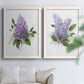 Set of two white barnwood framed canvas prints depicting layered lavender blossoms, broad foliage, and softly textured grounds arranged across two complementary compositions above a sofa in a bright living space.