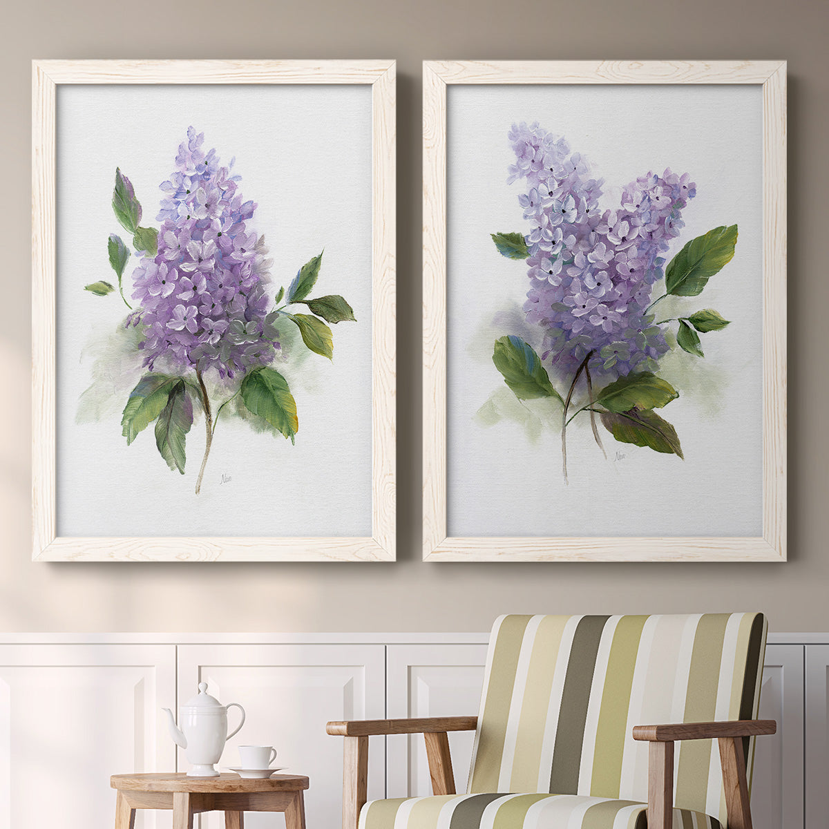 Set of two white barnwood framed canvas prints depicting two romantic traditional floral paintings featuring full purple lilac clusters with green leaves above a sideboard in a cozy sitting room.