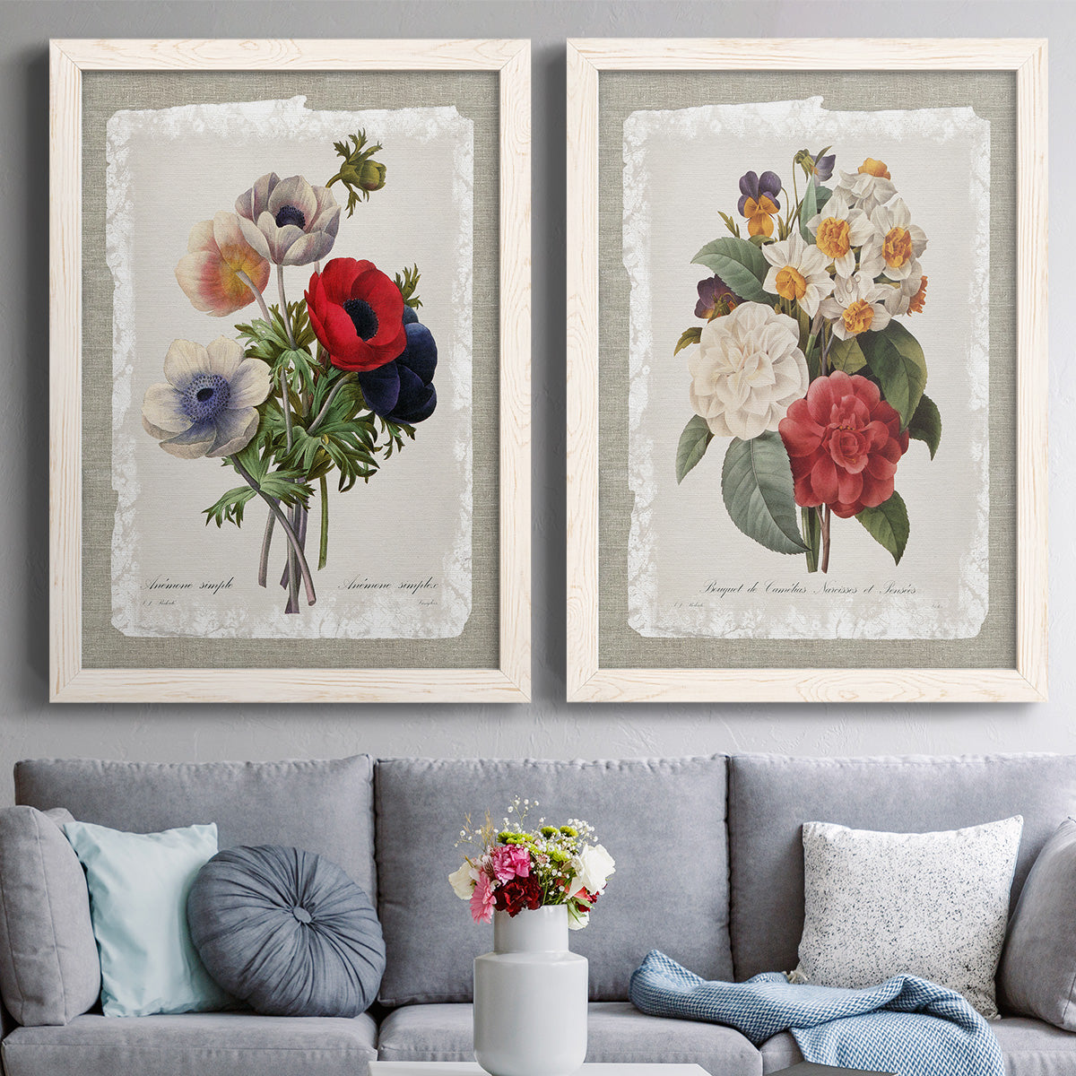 Set of two white barnwood framed canvas prints depicting paired traditional botanical collage prints with roses anemones carnations leaves and archival script details above a sofa in a contemporary living room.