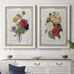 Set of two white barnwood framed canvas prints depicting a coordinated art pair of vintage mixed-flower bouquets on distressed paper rendered as traditional botanical collage prints above a dining room sideboard.