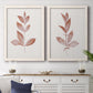 Set of two white barnwood framed canvas prints depicting a coordinated art pair of single rust-red leafy stems rendered as minimalist botanical prints above a dining room sideboard.