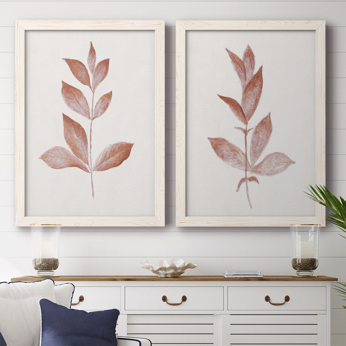 Set of two white barnwood framed canvas prints depicting a coordinated art pair of single rust-red leafy stems rendered as minimalist botanical prints above a dining room sideboard.