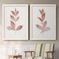 Set of two white barnwood framed canvas prints depicting two minimalist botanical prints featuring single rust-red leafy stems above a sideboard in a cozy sitting room.