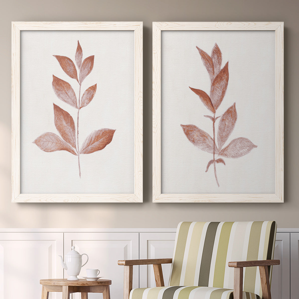 Set of two white barnwood framed canvas prints depicting two minimalist botanical prints featuring single rust-red leafy stems above a sideboard in a cozy sitting room.