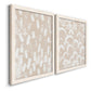 Angled view of a set of two white barnwood framed canvas prints featuring two tribal-inspired pattern abstracts featuring white hand-painted dashes arcs and chevrons.