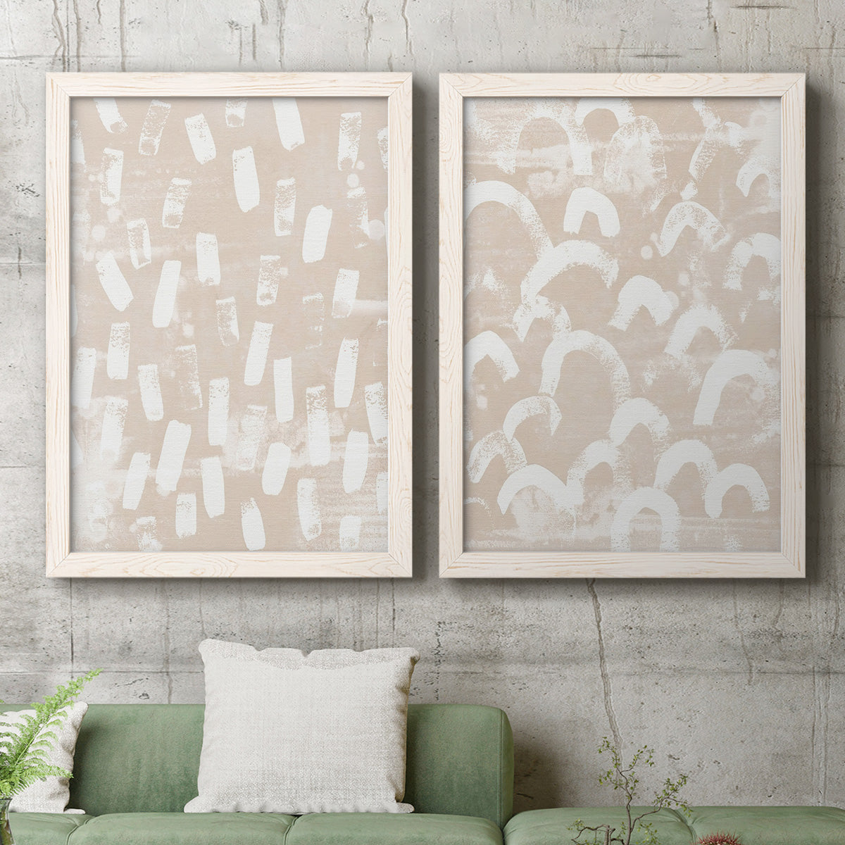Set of two white barnwood framed canvas prints depicting a coordinated art pair of white hand-painted dashes arcs and chevrons rendered as tribal-inspired pattern abstracts above a sofa in a modern living room.