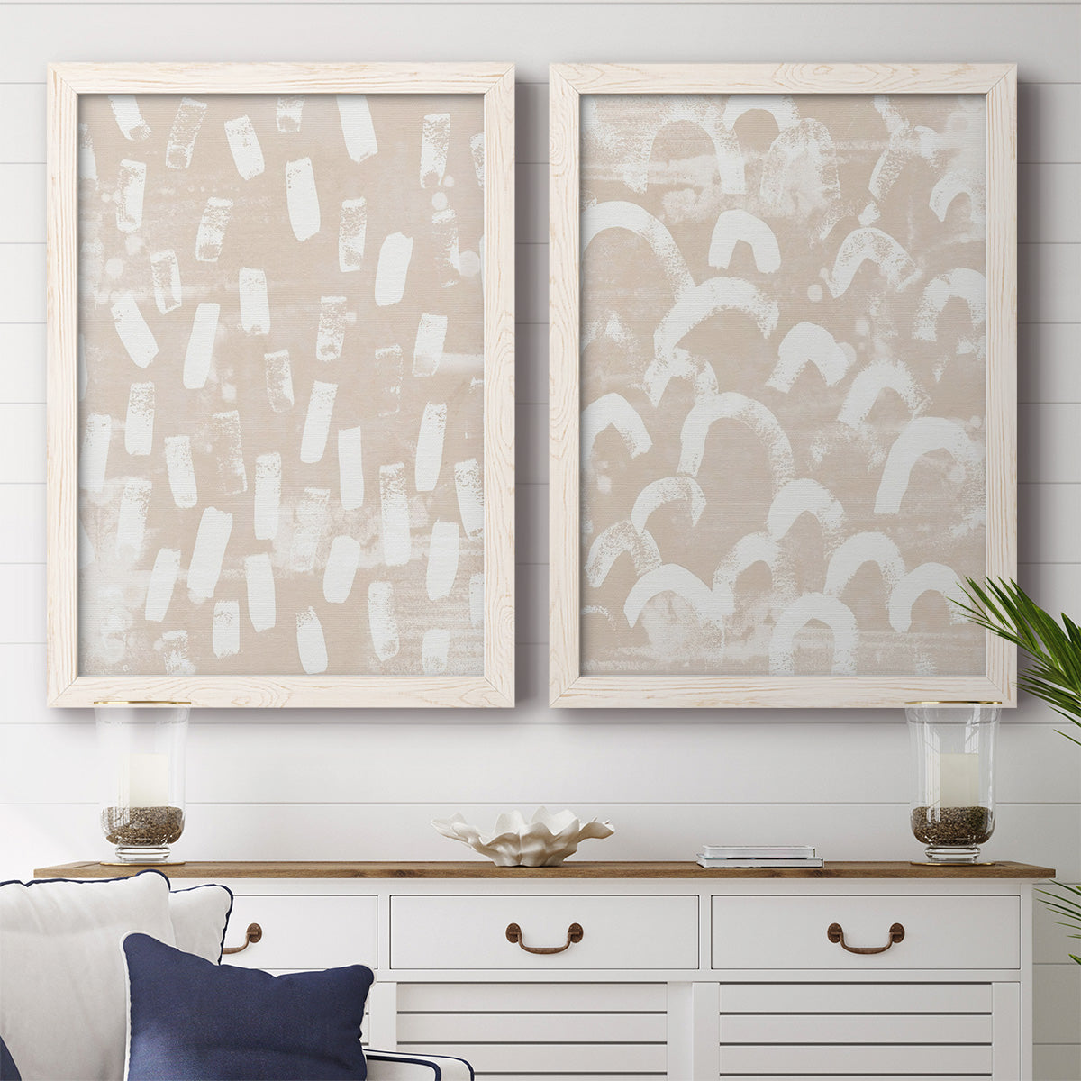 Set of two white barnwood framed canvas prints depicting a coordinated art pair of white hand-painted dashes arcs and chevrons rendered as tribal-inspired pattern abstracts above a dining room sideboard.