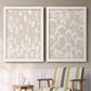 Set of two white barnwood framed canvas prints depicting two tribal-inspired pattern abstracts featuring white hand-painted dashes arcs and chevrons above a sideboard in a cozy sitting room.