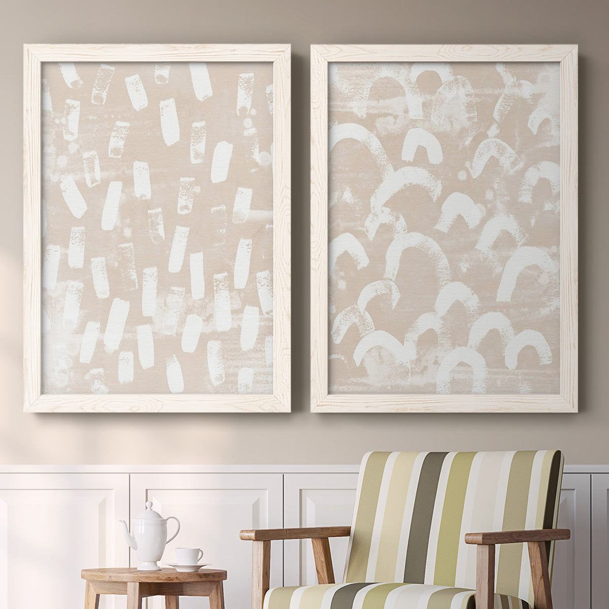 Set of two white barnwood framed canvas prints depicting two tribal-inspired pattern abstracts featuring white hand-painted dashes arcs and chevrons above a sideboard in a cozy sitting room.