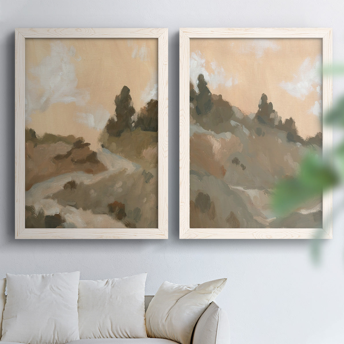 Set of two white barnwood framed canvas prints depicting layered ridges, soft earth tones, and hazy cream skies arranged across two complementary compositions above a sofa in a bright living space.