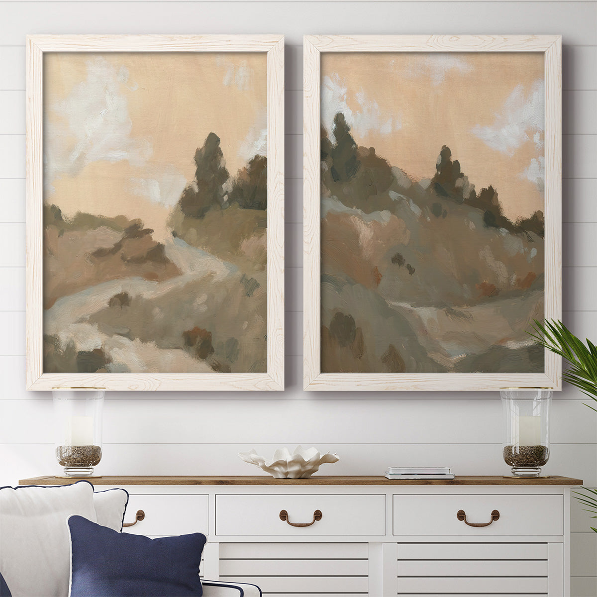 Set of two white barnwood framed canvas prints depicting a coordinated art pair of misty brown hills and winding mountain paths rendered as minimalist watercolor landscapes above a dining room sideboard.