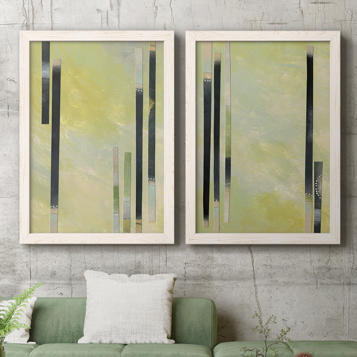 Set of two white barnwood framed canvas prints depicting a coordinated art pair of vertical black gray and olive bars rendered as minimalist architectural abstracts above a sofa in a modern living room.