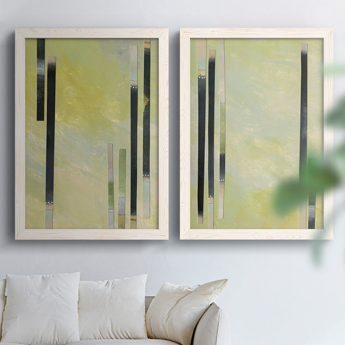 Set of two white barnwood framed canvas prints depicting slender rectangular elements, pale yellow fields, and subtle layered texture arranged across two complementary compositions above a sofa in a bright living space.