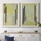Set of two white barnwood framed canvas prints depicting a coordinated art pair of vertical black gray and olive bars rendered as minimalist architectural abstracts above a dining room sideboard.