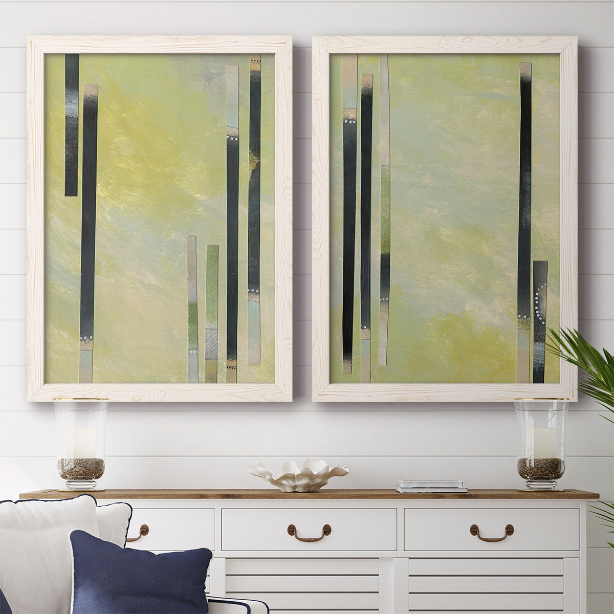 Set of two white barnwood framed canvas prints depicting a coordinated art pair of vertical black gray and olive bars rendered as minimalist architectural abstracts above a dining room sideboard.