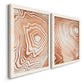 Angled view of a set of two white barnwood framed canvas prints featuring two minimalist marbled pattern abstracts featuring concentric wood-grain rings and rippling contour lines.